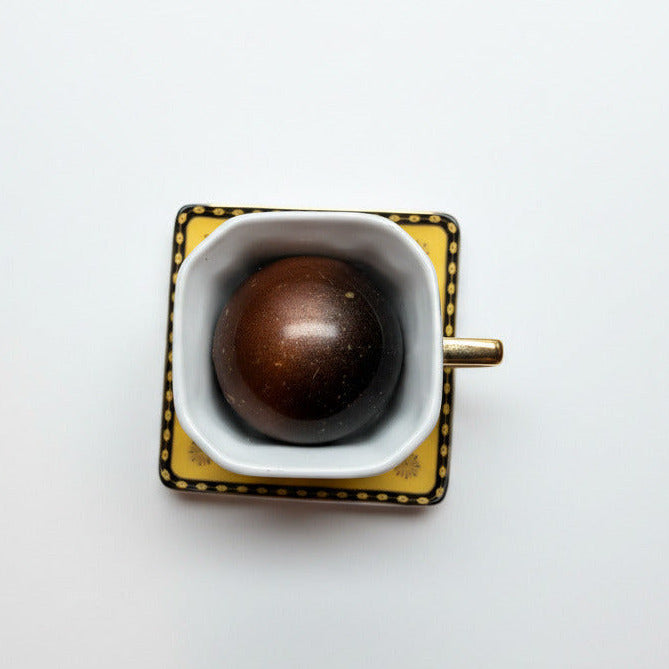 Square mug with a dark brown object on a light speckled surface