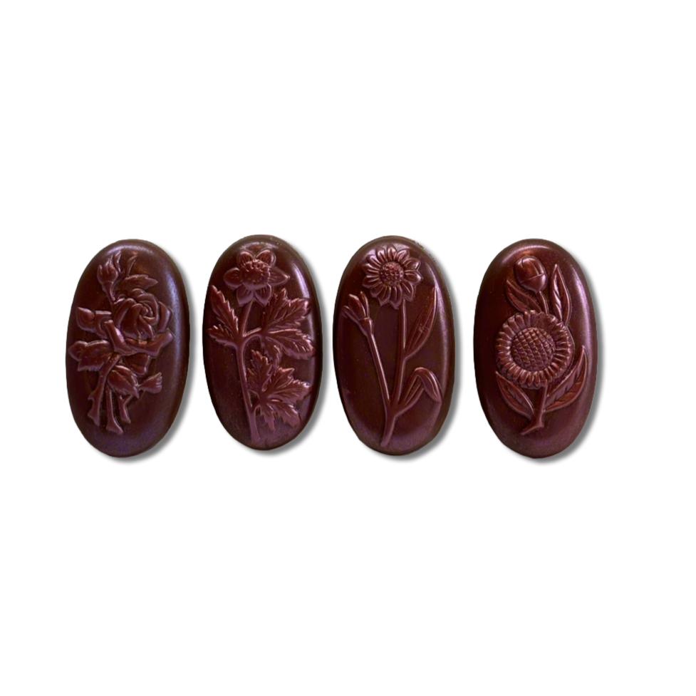Four brown oval chocolates with floral engravings on a white background
