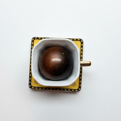Square mug with a dark brown object on a light speckled surface