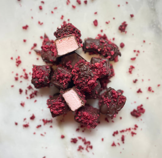 Handcrafted artisan marshmallows with a dark chocolate coating and pieces of a raspberry.